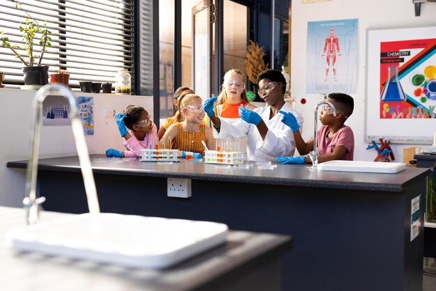 Foto diversas professoras e crianças de escola fazendo uma experiência na aula de química