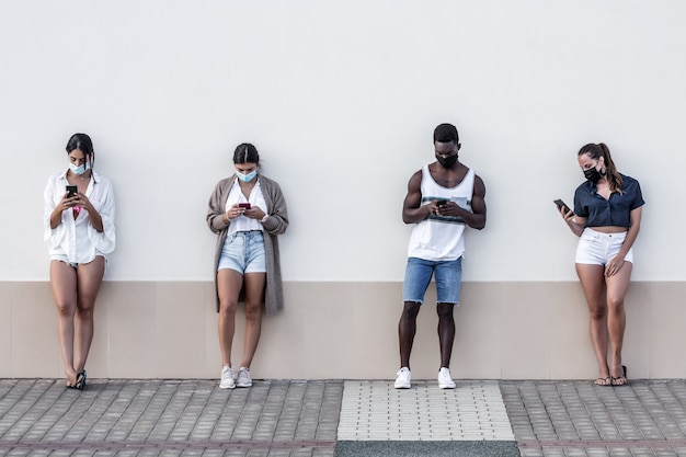 Diverse Freunde, die auf der Straße Smartphones surfen