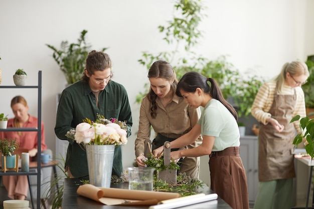 Diverse Gruppe junger Floristen, die während des Workshop-Kurses Blumenkompositionen erstellen, Platz kopieren