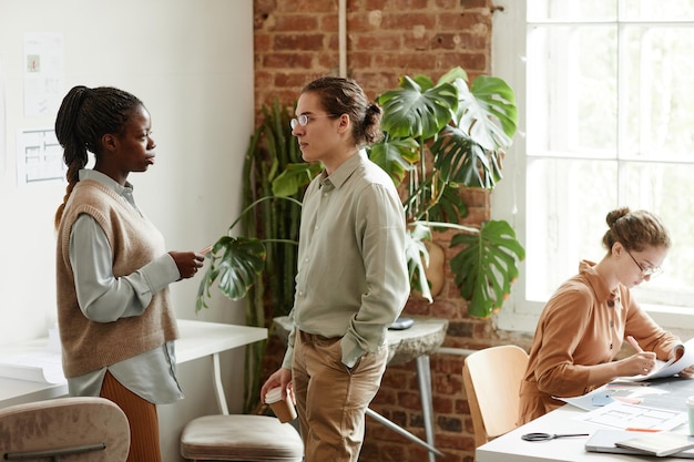 Diverse Gruppe kreativer junger Leute, die in minimalem Studio an Designprojekten arbeiten, Kopierraum