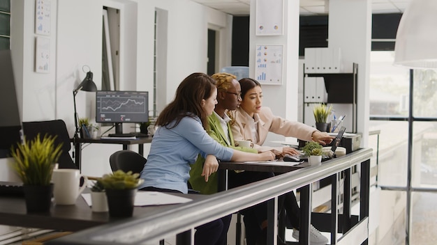 Diverse Startup-Teams planen Investitionen im Büro und nehmen an einem Briefing-Meeting im Coworking Space teil. Junge Frauen überprüfen Analysedaten auf Computern und Dateien und finden Geschäftslösungen.