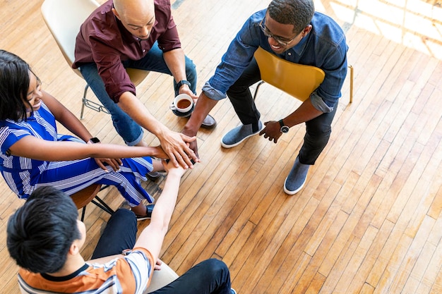 Diverse Teams, die Hände in der Mitte stapeln