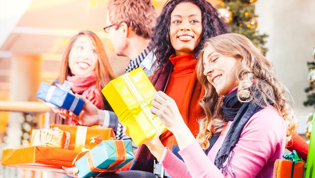 Diversidad Amigos con regalos de Navidad y bolsas de compras en el centro comercial