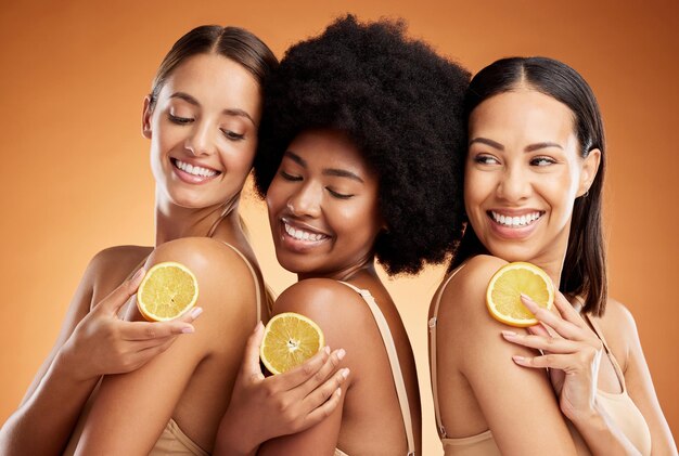 Diversidad de cuidado de la piel y belleza de las mujeres y limón para el bienestar de la salud y la nutrición en el fondo del estudio naranja Amigos sonríen y modelos felices con fruta para una piel sana o brillante con vitamina c