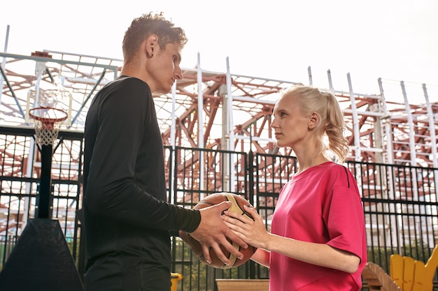 Diversidad jugando al baloncesto una chica toma la pelota de un tipo durante un juego de streetball