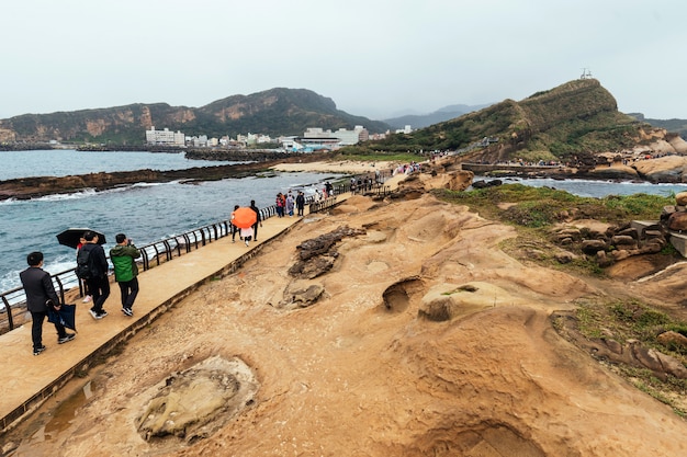 Diversidade da vista aérea dos turistas que andam em Yehliu Geopark, um cabo na costa norte de Taiwan. Uma paisagem de rochas de favo de mel e cogumelos corroídas pelo mar.