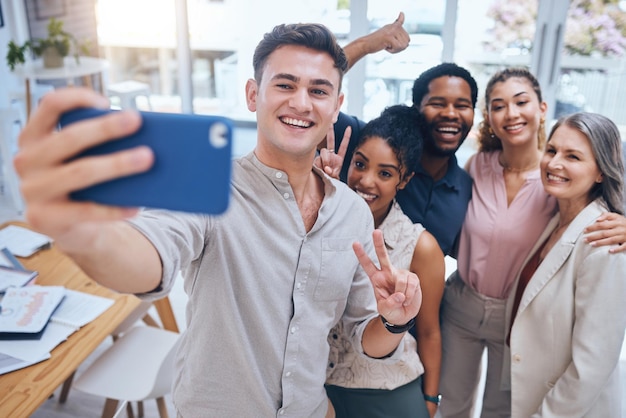 Diversidade de selfie e trabalho em equipe com empresários felizes mostrando sinal de paz no escritório de inicialização Local de trabalho positivo e engajamento de funcionários para motivação com funcionários saudáveis em um ambiente de trabalho divertido