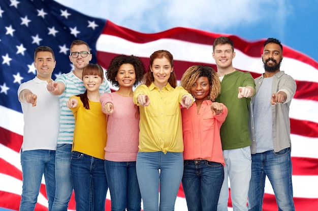 Foto diversidade, escolha, etnia e conceito de pessoas - grupo internacional de homens e mulheres sorridentes felizes apontando o dedo para você sobre o fundo da bandeira americana