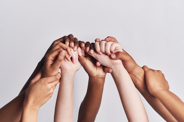 Diversificado como um todo Tiro de um grupo de mãos segurando umas às outras contra um fundo branco