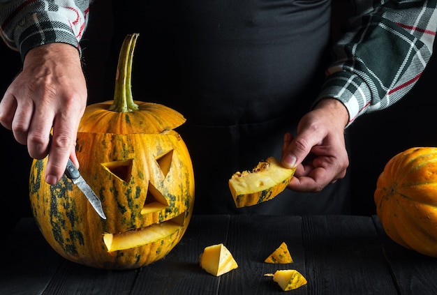 Diversión familiar o preparación para fiestas. Linterna cortada de una calabaza para el primer plano de Halloween. Primer plano de una persona es manos mientras trabaja.