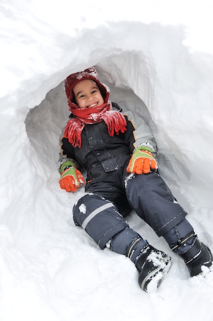 Diversión de invierno niño jugando divirtiéndose en la nieve