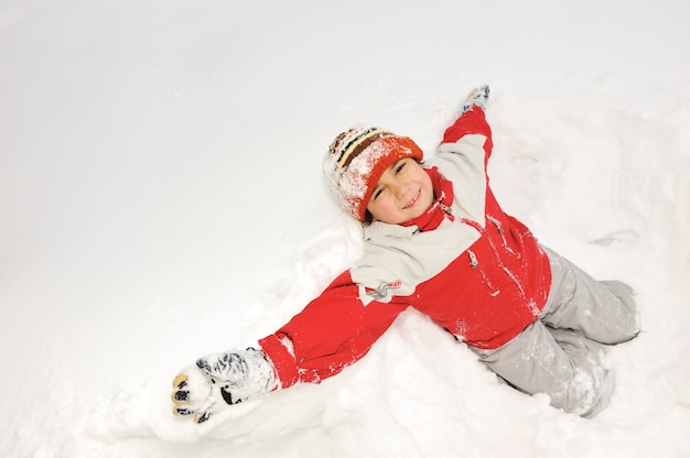 Diversión de invierno niño jugando divirtiéndose en la nieve