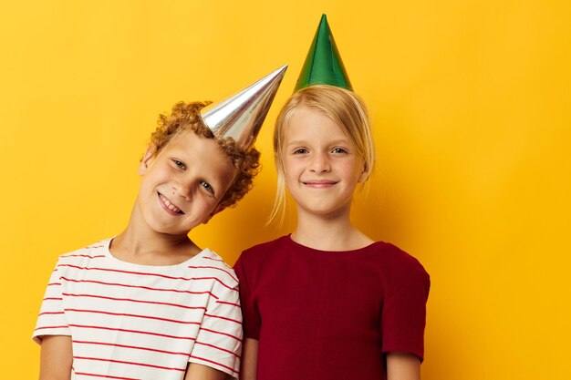 Diversión de vacaciones para niños pequeños con gorras en la cabeza fondo amarillo