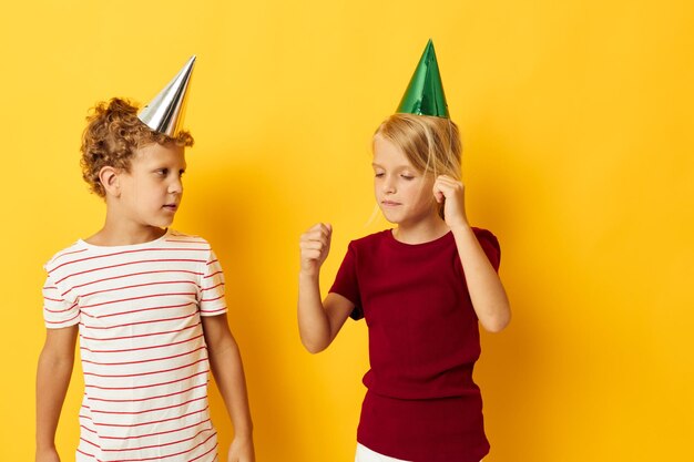 Diversión de vacaciones para niños pequeños con gorras en la cabeza fondo amarillo