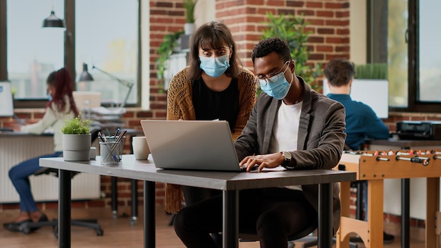 Diverso equipo de compañeros de trabajo analizando información de gráficos en documentos, utilizando datos de investigación para planificar proyectos de negocios. Creación de presentación en línea con informe corporativo y plan exitoso.