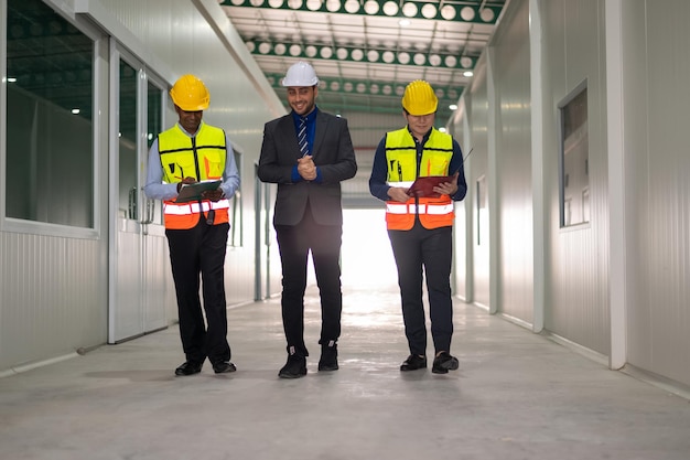 Diverso equipo de especialistas dando un paseo por el proyecto de construcción de bienes raíces en el sitio de la fábrica con el ingeniero civil senior arquitecto trabajador general discutiendo los detalles de planificación y desarrollo