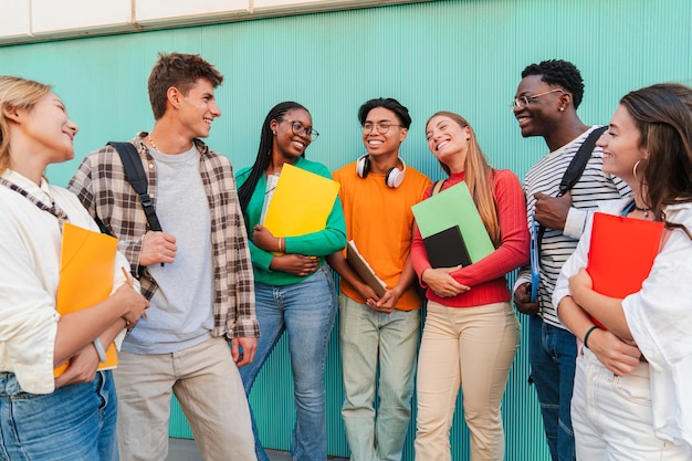 Diverso grupo de estudiantes hablando y sonriendo al aire libre jóvenes amigos con cuadernos y mochilas