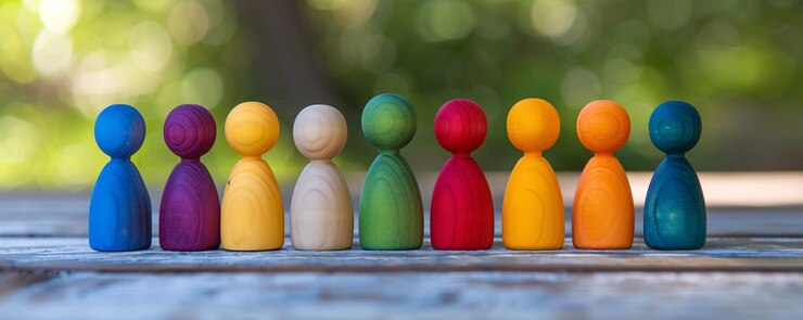 Diverso grupo de personas representadas por figuras de madera vibrantes de pie en una línea