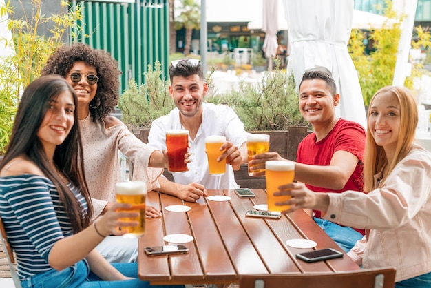 Diversos amigos tintinean vasos de cerveza