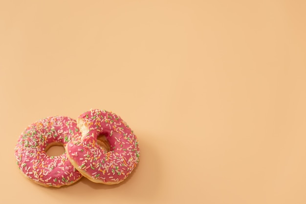 Diversos buñuelos adornados en el movimiento que cae en fondo rosado. Dulces y coloridos donuts cayendo o volando en movimiento.