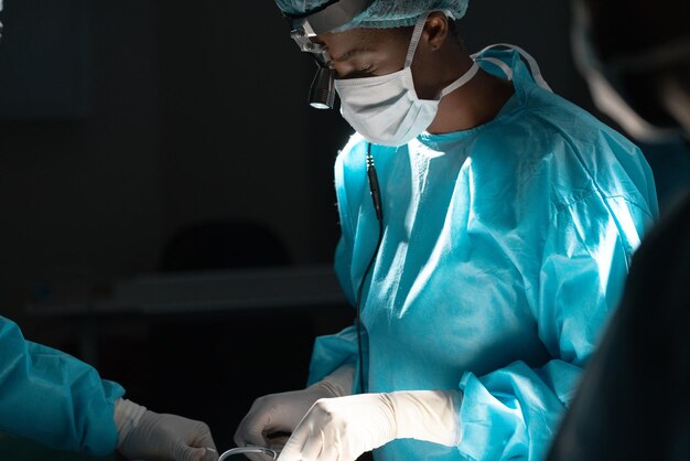 Foto diversos cirujanos con batas quirúrgicas operando a un paciente en el quirófano del hospital