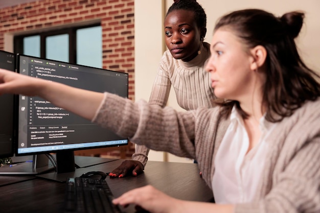 Diversos codificadores trabajando en la ventana de terminal con script html, escribiendo código de servidor en la computadora, sentados en el escritorio en la sala de big data.