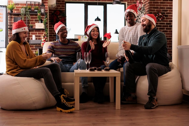 Diversos colegas de trabalho comemorando o natal na festa de emprego, bebendo vinho em copos e se divertindo na temporada de férias de inverno. Escritório festivo com árvore de natal e decoração sazonal, bebida alcoólica.