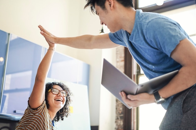 Diversos colegas felizes em uma empresa iniciante fazendo um high five