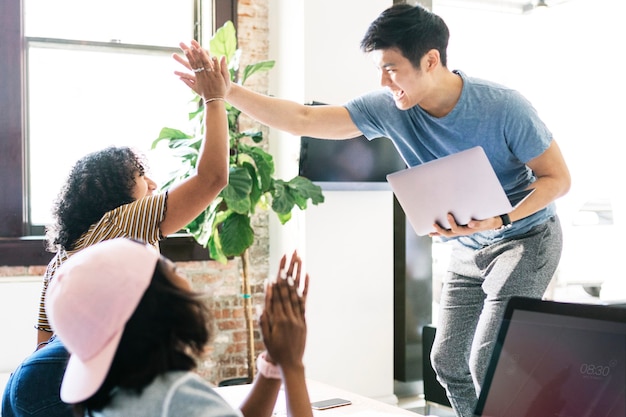 Diversos colegas felizes em uma empresa iniciante fazendo um high five