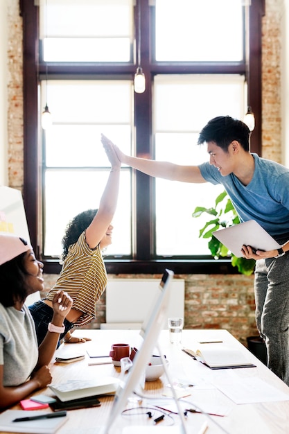 Diversos colegas felizes em uma empresa iniciante fazendo um high five