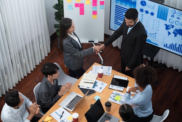 Diversos compañeros de trabajo celebran con un apretón de manos y trabajo en equipo en el lugar de trabajo corporativo Personas de negocios felices unidas por un apretón de manos después de una reunión exitosa o una presentación de negocios sobre análisis de datos Concord