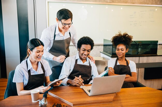 Diversos empresarios en una elegante cafetería tienen una reunión de equipo El dueño del barista discute el trabajo en la computadora portátil Empleados multiétnicos discusión de negocios de trabajo en equipo exitoso