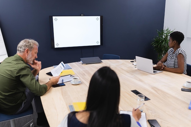 Diversos empresários na sala de conferências olhando para o monitor em branco. brainstorming de reunião de negócios de escritório criativo.