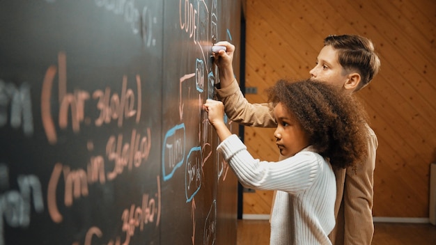 Foto diversos estudiantes felices hacen una tormenta de ideas sobre ingeniería en la pizarra.