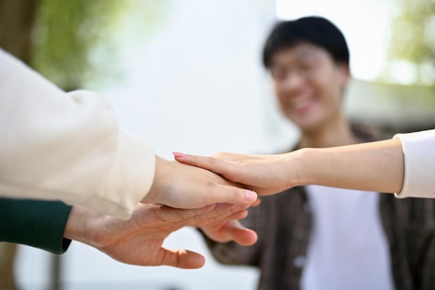 Diversos estudiantes universitarios juntando sus manos para animar la amistad del trabajo en equipo