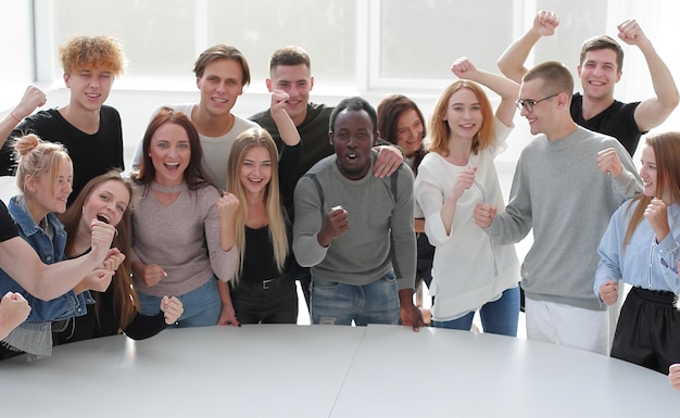 Diversos jóvenes de pie cerca de una mesa redonda