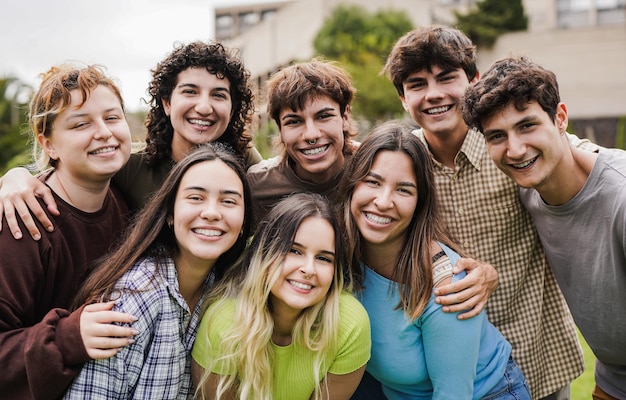 Diversos jóvenes sonriendo a la cámara fuera de la universidad