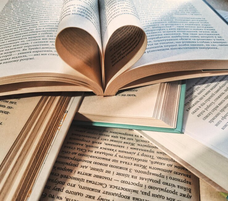 Diversos libros con un libro abierto y hojas rizadas en forma de corazón Educación y aprendizaje de la lectura