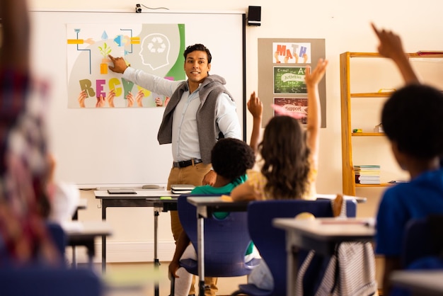 Diversos maestros masculinos enseñando y niños de escuela primaria levantando la mano en clase