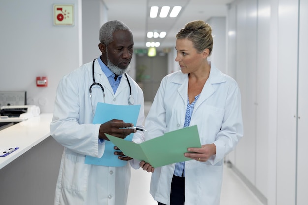 Diversos médicos, homens e mulheres, parados no corredor do hospital, olhando para documentação médica
