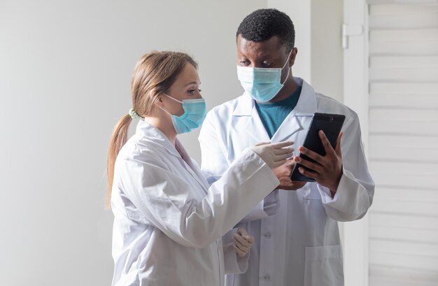 Foto diversos médicos masculinos y femeninos con máscaras médicas blancas