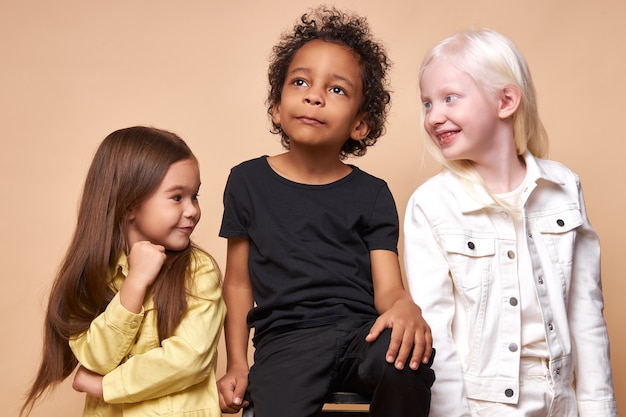 Diversos niños positivos sonrientes posando felices juntos