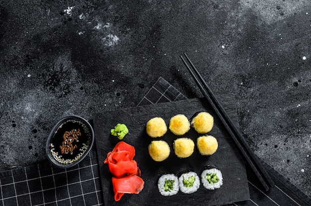 Foto diversos tipos de sushi servido en piedra negra. vista superior
