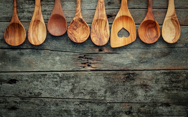 Diversos utensilios de cocinar de madera en fondo de madera lamentable.