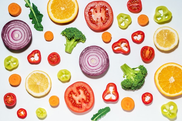 Diversos vegetais fatiados e frutas na superfície branca.