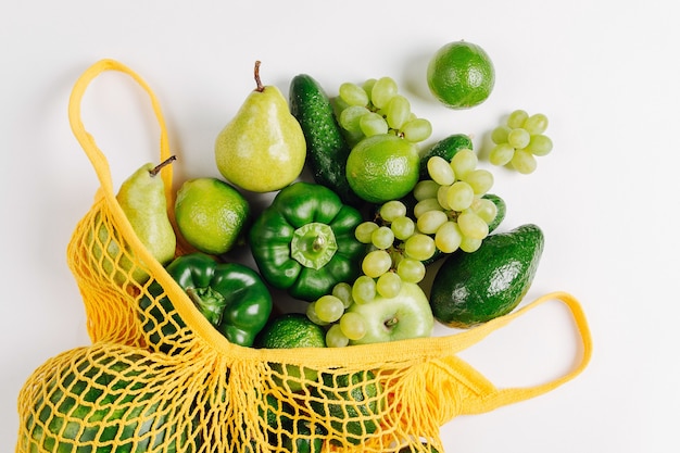 Diversos vegetais verdes orgânicos frescos variados em bolsa de malha amarela, postura plana, vista superior