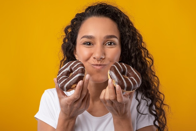 Divertida dama latina sosteniendo pastel de rosquilla de mascar en el estudio