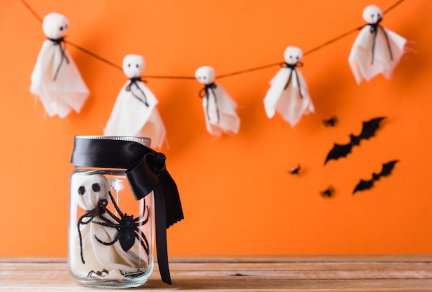 Divertida fiesta de decoración del día de Halloween Bebé fantasma blanco manualidades cara de miedo en tarro de vidrio sobre mesa de madera