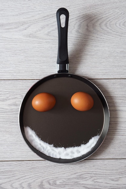 Divertida imagen de una cara hecha de huevos sal en una sartén