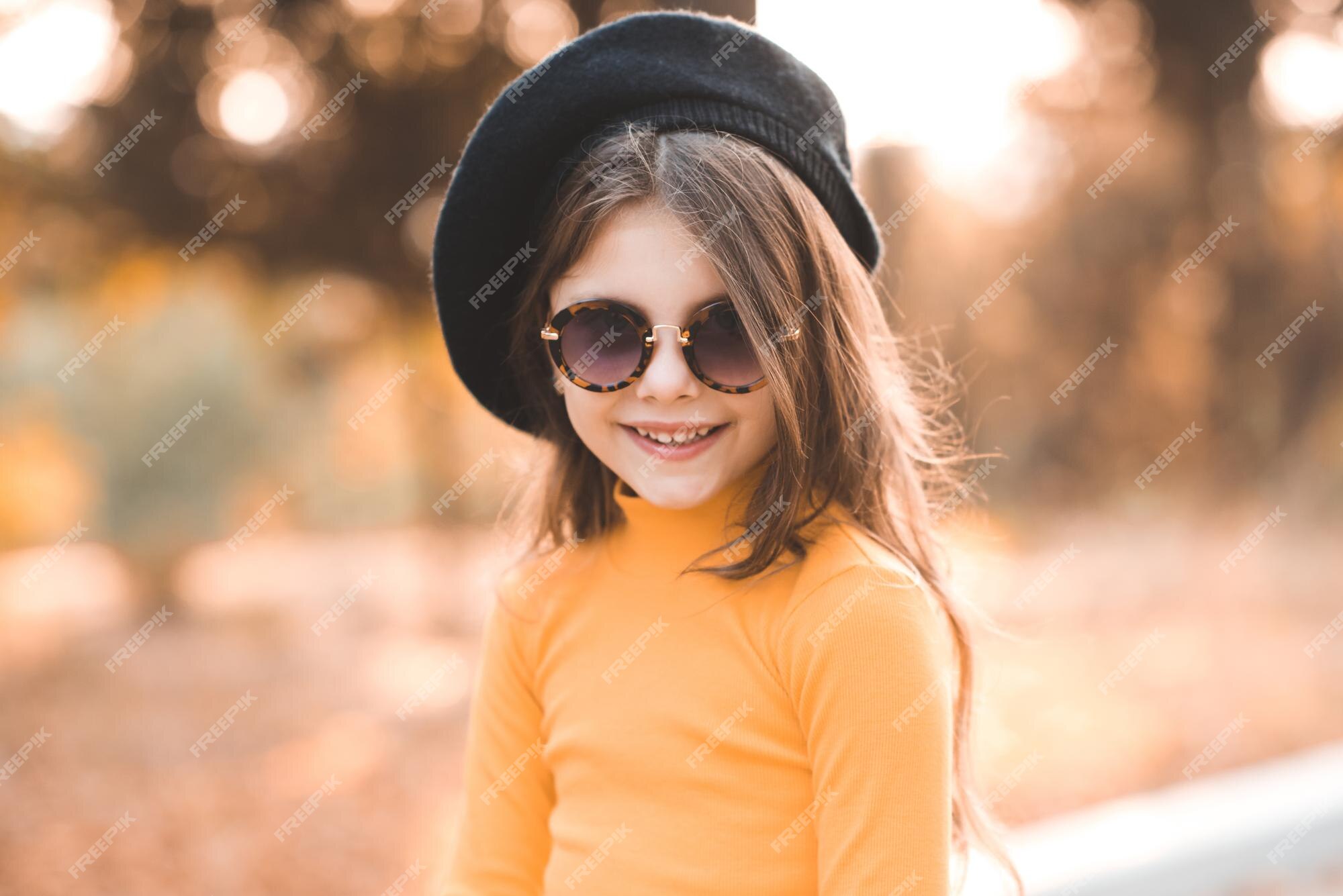 Divertida y linda niña de 4 a 5 años que usa gafas de y un vestido de punto amarillo posando sobre la naturaleza en | Foto Premium